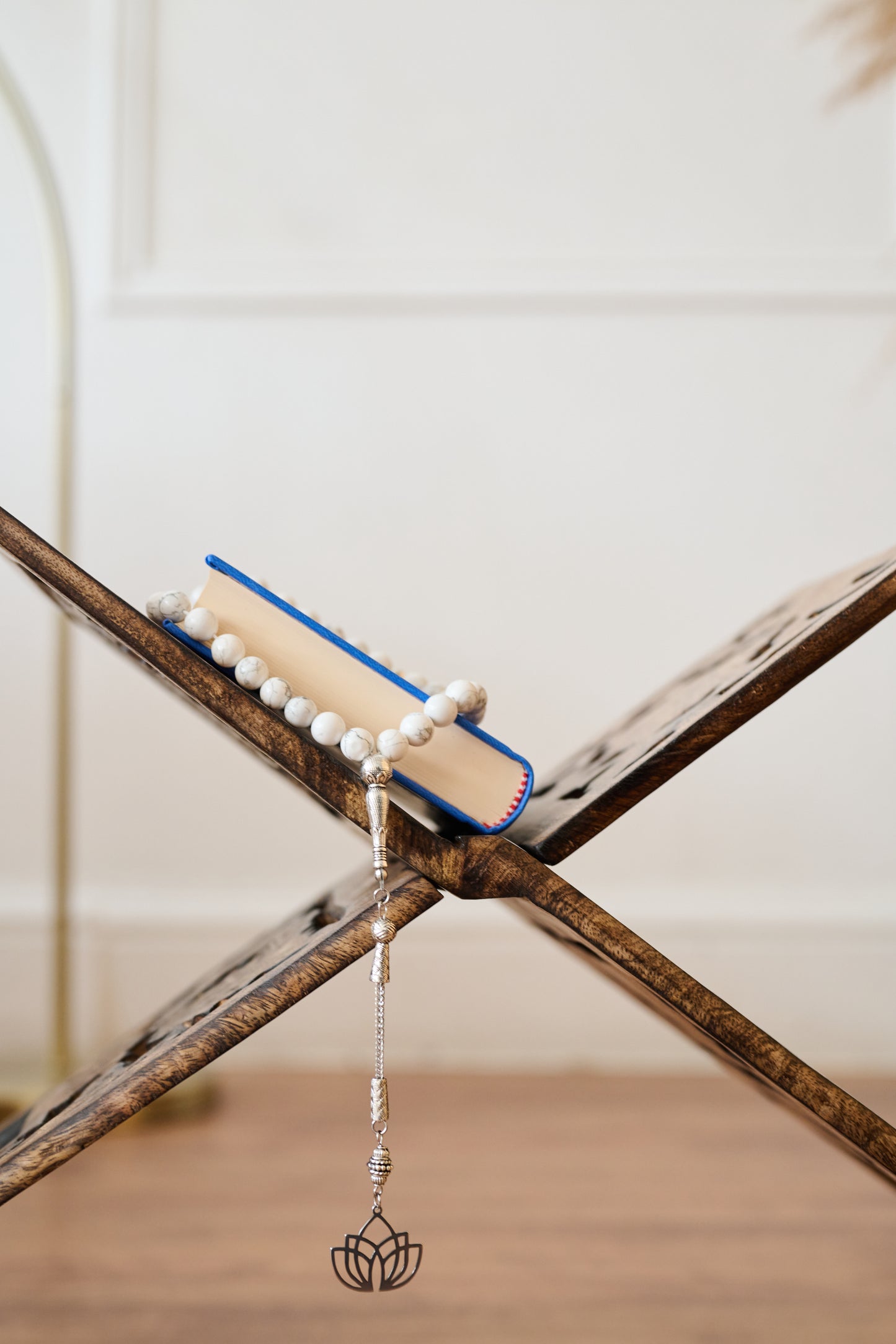 Book with a bookmark featuring pearls and a decorative element on a wooden surface.