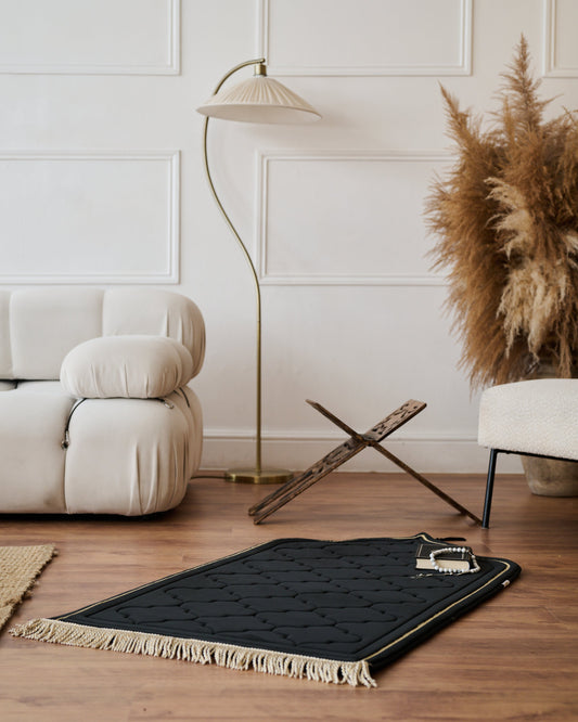 Black rug with tassels on a wooden floor in a living room setting.