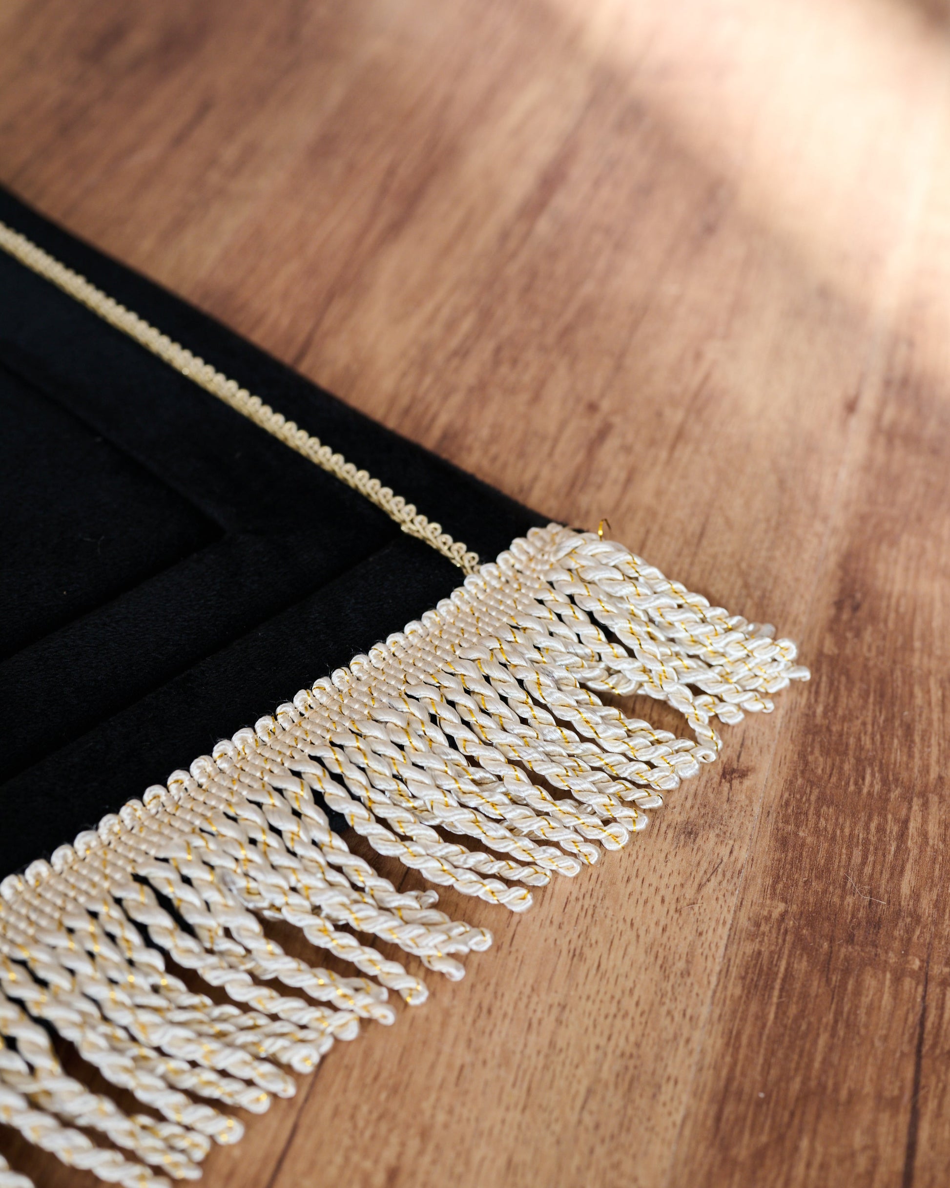Close-up of a decorative fringe on a wooden surface