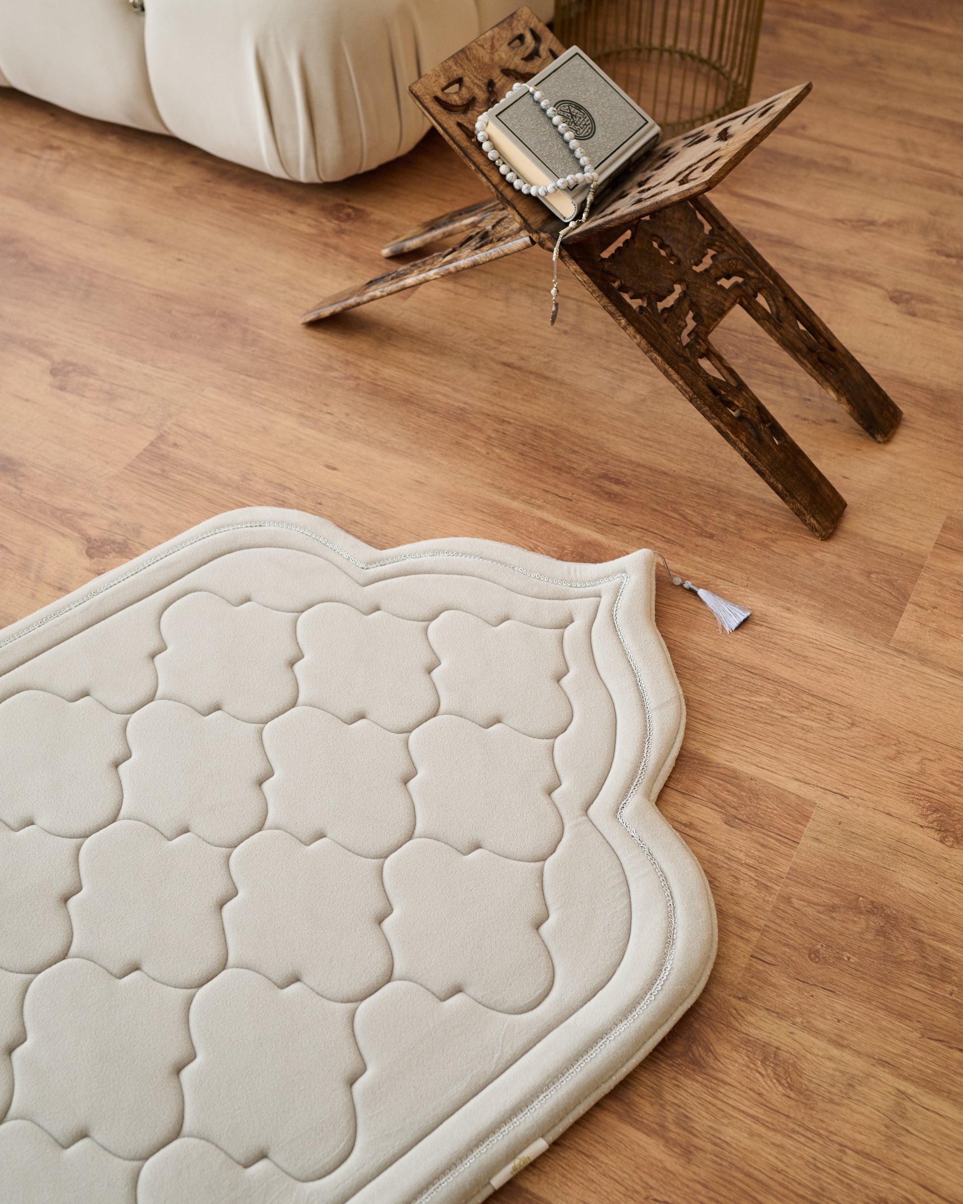 textured memory foam prayer mat on a wooden floor with a modern sofa and decor in the background.