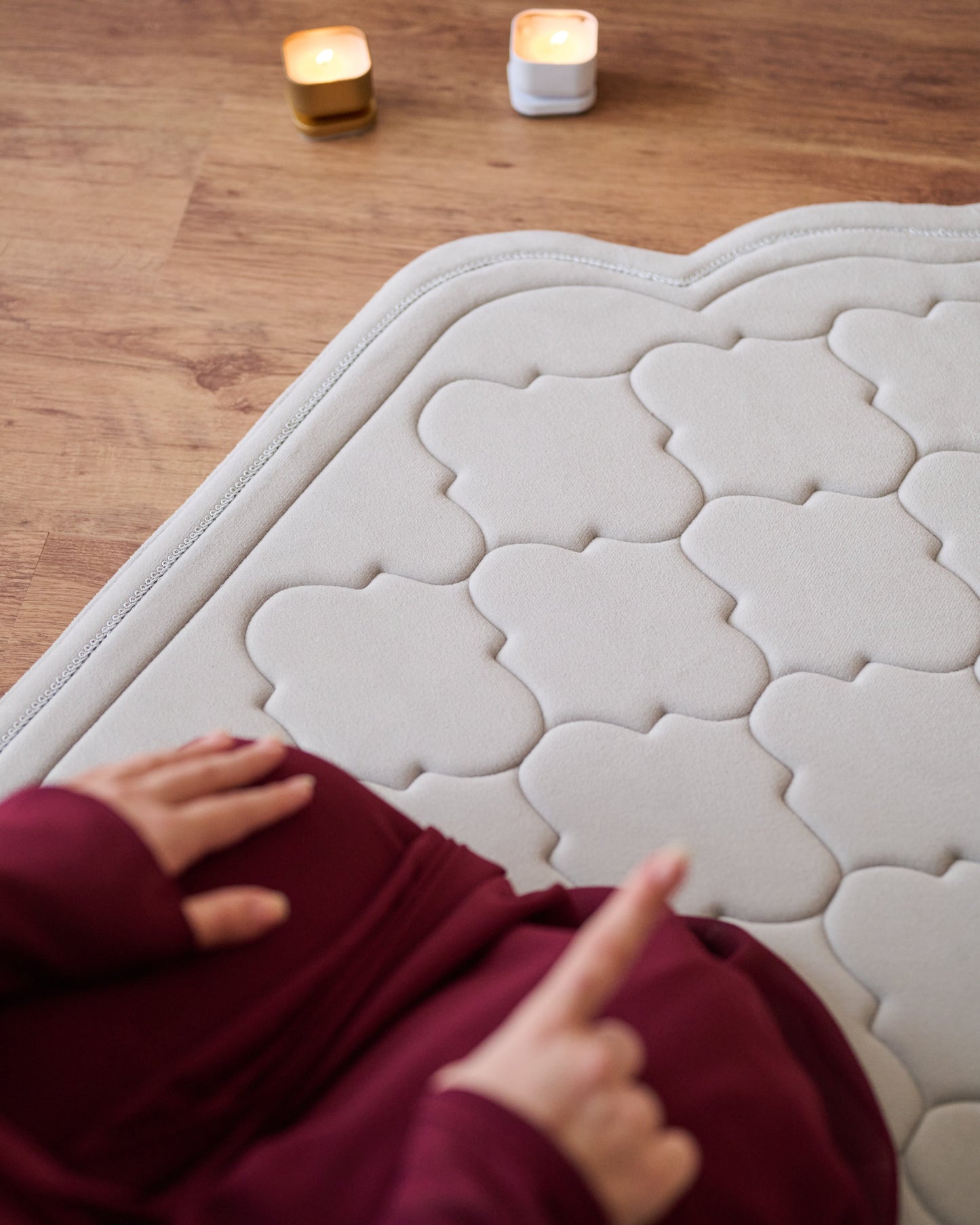 textured memory foam prayer mat on a wooden floor with a modern sofa and decor in the background.