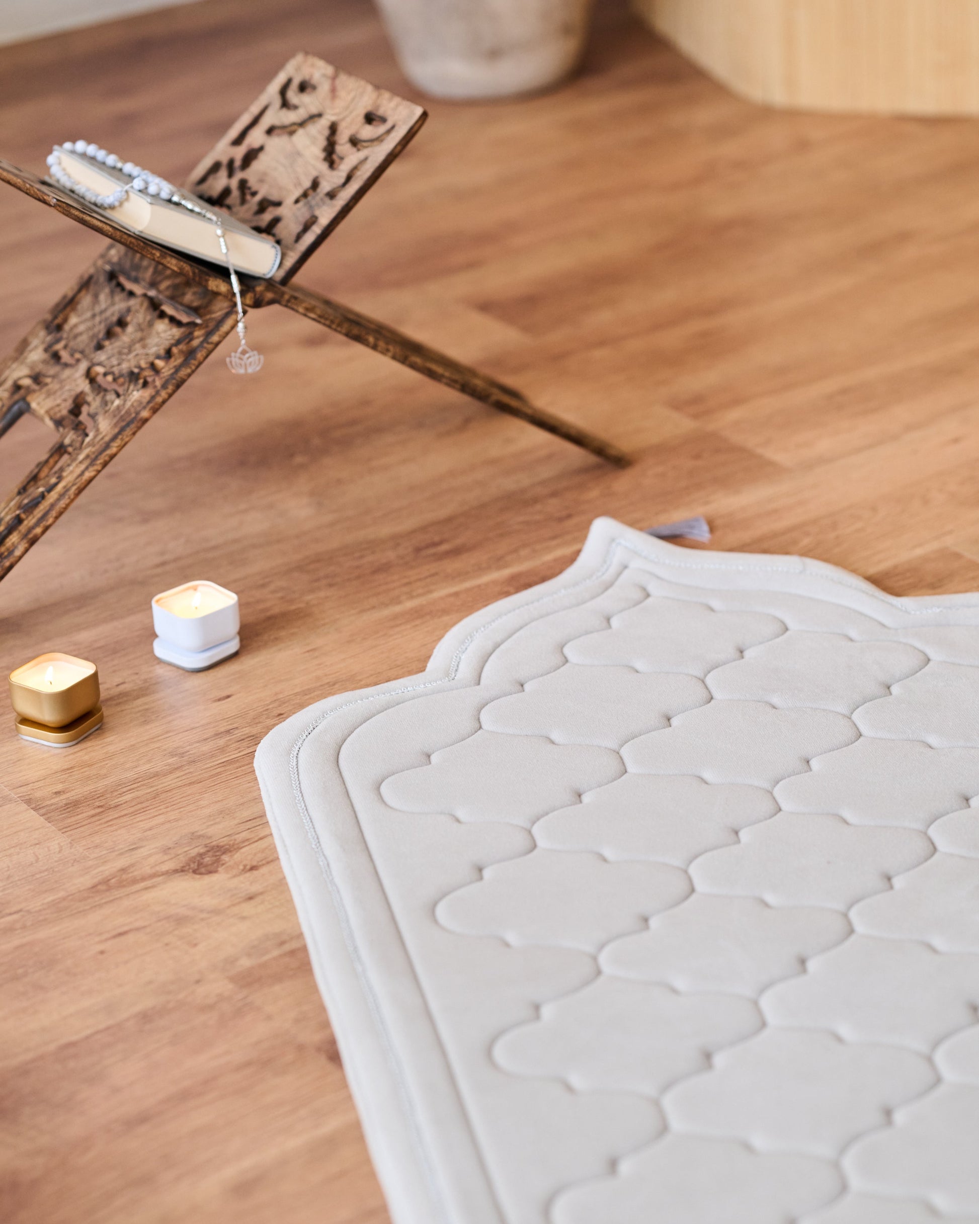 textured memory foam prayer mat on a wooden floor with a modern sofa and decor in the background.