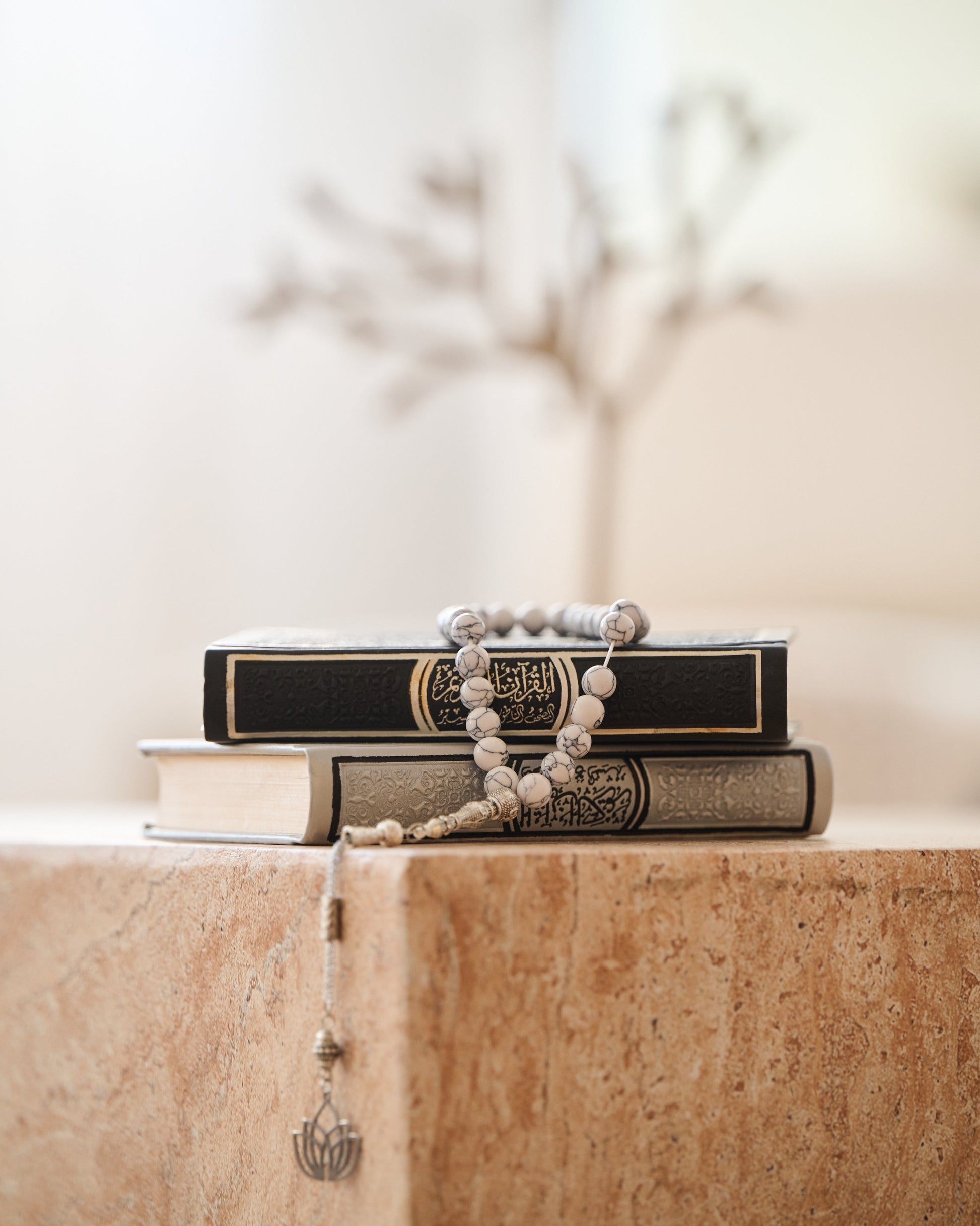 Stack of books with a rosary on a stone surface